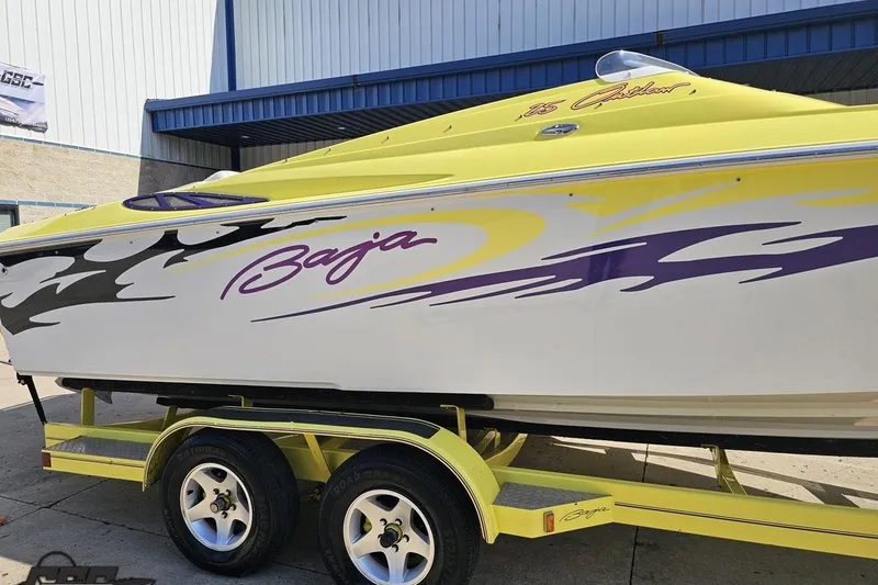 Slide: The Image of 2005 Baja 25 Outlaw speedboat with vibrant yellow and purple graphics on a trailer. - 6