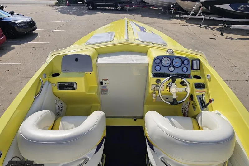 Slide: The Image of 2005 Baja 25 Outlaw boat interior with yellow dashboard and white seats. - 61