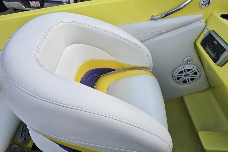 Slide: The Image of 2005 Baja 25 Outlaw boat interior with white and yellow seating, stereo, and speakers. - 75
