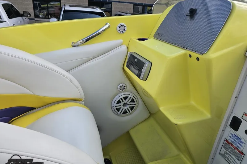 Slide: The Image of 2005 Baja 25 Outlaw boat interior with yellow and white seating, audio system, and speakers. - 76