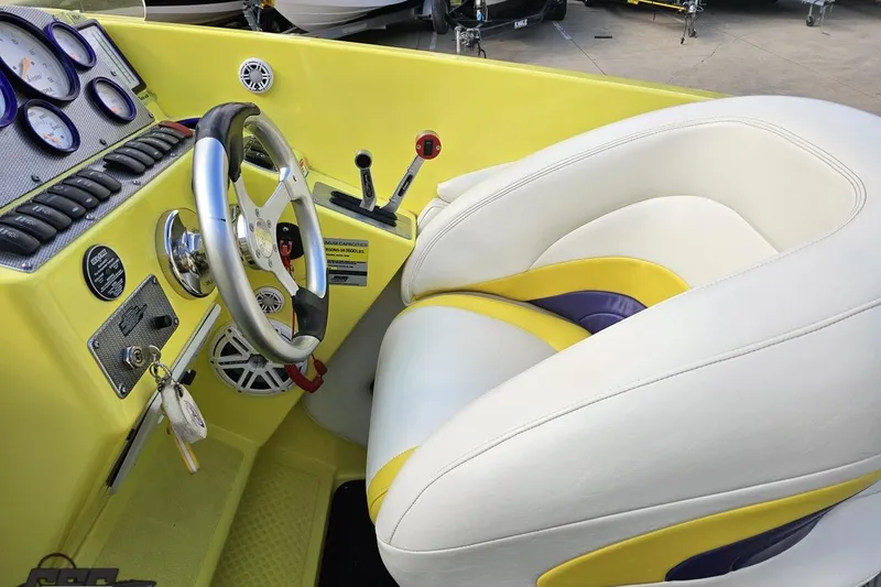 Slide: The Image of 2005 Baja 25 Outlaw boat cockpit with yellow dashboard and white seats. - 77