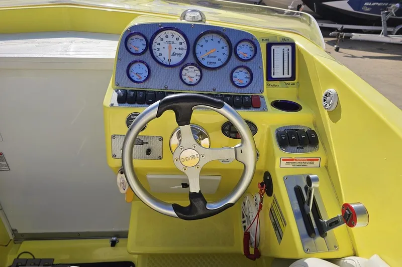 Slide: The Image of 2005 Baja 25 Outlaw boat dashboard with steering wheel and gauges, featuring a vibrant yellow design. - 79