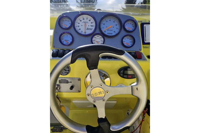 Slide: The Image of Steering wheel and dashboard of a 2005 Baja 25 Outlaw boat, featuring multiple gauges. - 80