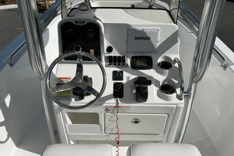 Slide: The Image of 2016 Sea Hunt Triton 225 boat console with steering wheel, Simrad display, and controls. - 10