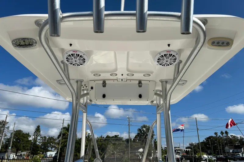 Slide: The Image of 2016 Sea Hunt Triton 225 boat T-top with speakers and rod holders under a clear sky. - 14