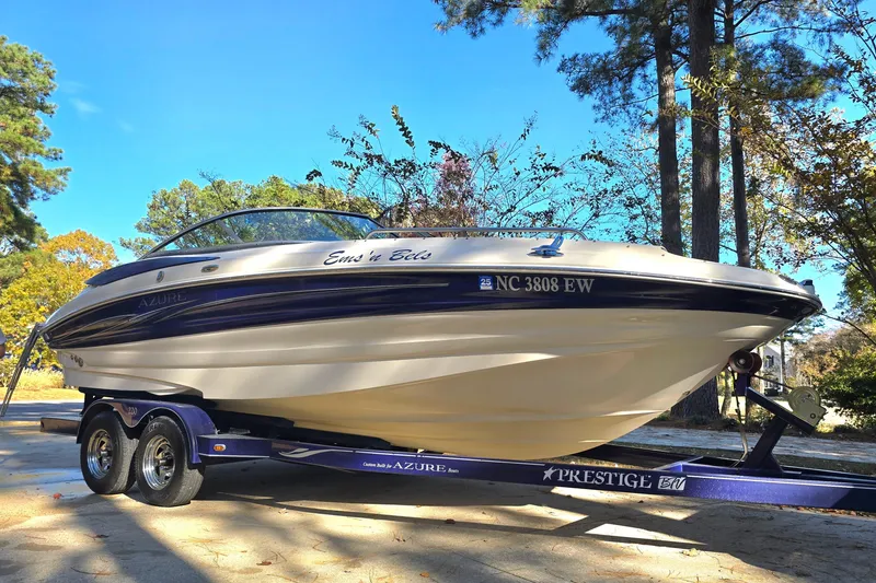 Slide: The Image of 2006 Azure AZ 220 boat on trailer, parked outdoors with trees in background. - 21