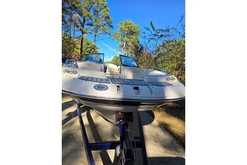 Slide: The Image of 2006 Azure AZ 220 boat on trailer, surrounded by trees under clear blue sky. - 34