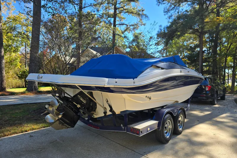 Slide: The Image of 2006 Azure AZ 220 boat on trailer, covered with blue tarp, parked in wooded driveway. - 4