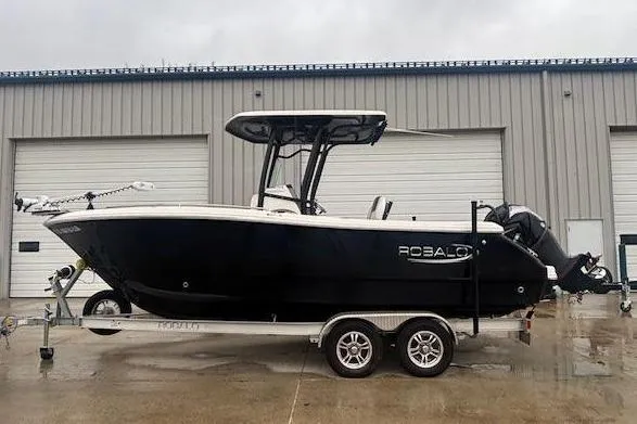 The Image of 2021 Robalo R230 Center Console boat on trailer, parked outside industrial building. - 0