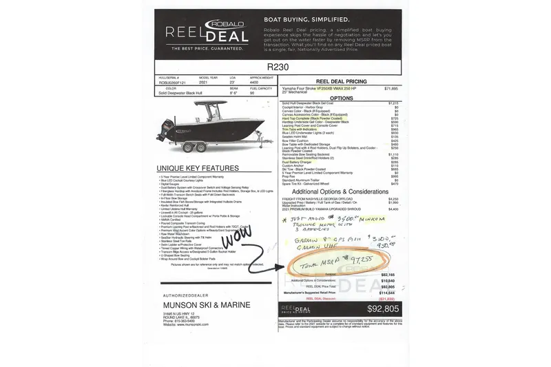 Slide: The Image of 2021 Robalo R230 Center Console boat on trailer, parked outside a warehouse. - 2