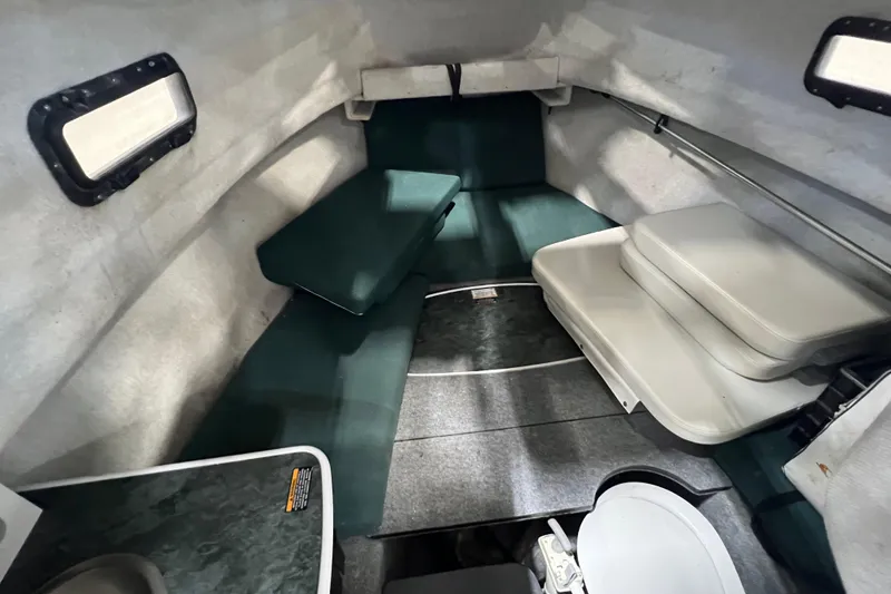 Slide: The Image of 2006 Trophy 2352 WA cabin interior with green cushions and compact layout. - 18