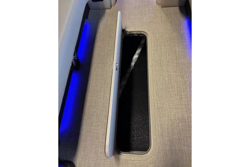 Slide: The Image of 2026 Tahoe Pontoon Grand Tahoe LTD Quad Lounge interior storage compartment with blue LED lighting. - 7