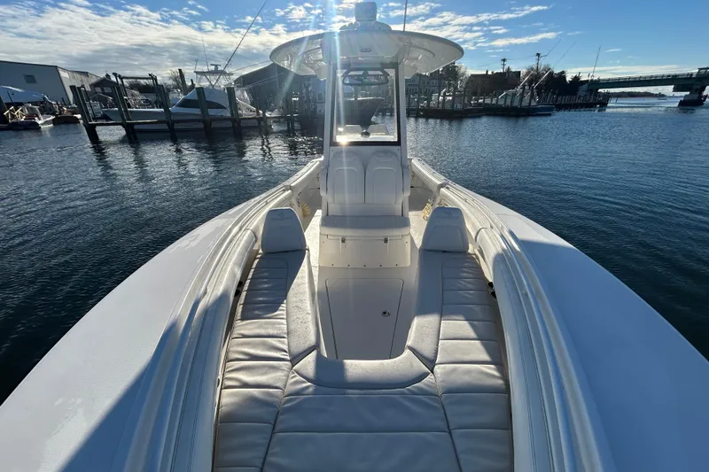 Slide: The Image of 2022 Regulator 25 boat with cushioned seating, docked in a marina under a sunny sky. - 17
