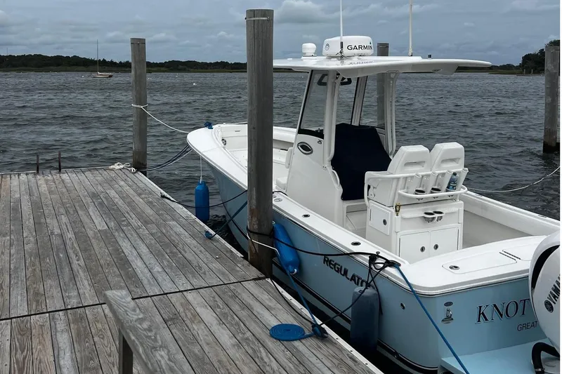 Slide: The Image of 2022 Regulator 25 boat with twin engines navigating a marina. - 3