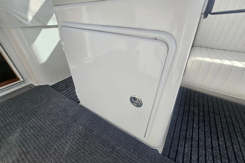 Slide: The Image of 2003 Topaz 32 Express boat interior with white storage compartment and striped flooring. - 27