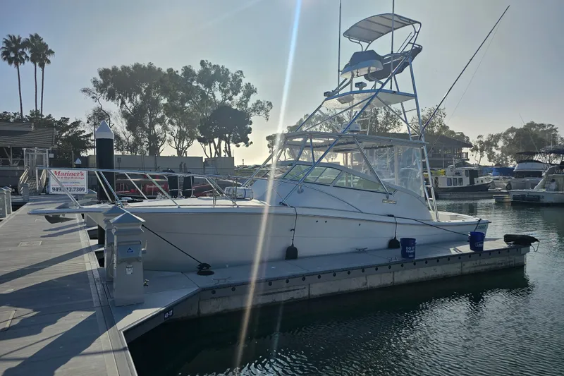Slide: The Image of 2003 Topaz 32 Express boat docked at marina with clear sky and trees in background. - 4