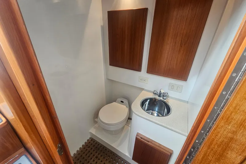Slide: The Image of 2003 Topaz 32 Express boat bathroom with toilet, sink, and wooden cabinetry. - 51