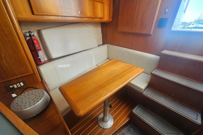 Slide: The Image of 2003 Topaz 32 Express cabin interior with wooden table, white seating, and stairs. - 59