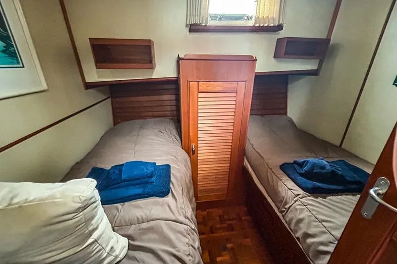 Slide: The Image of Cozy twin cabin on 1998 Grand Banks 46 Europa yacht with wooden accents and natural light. - 5