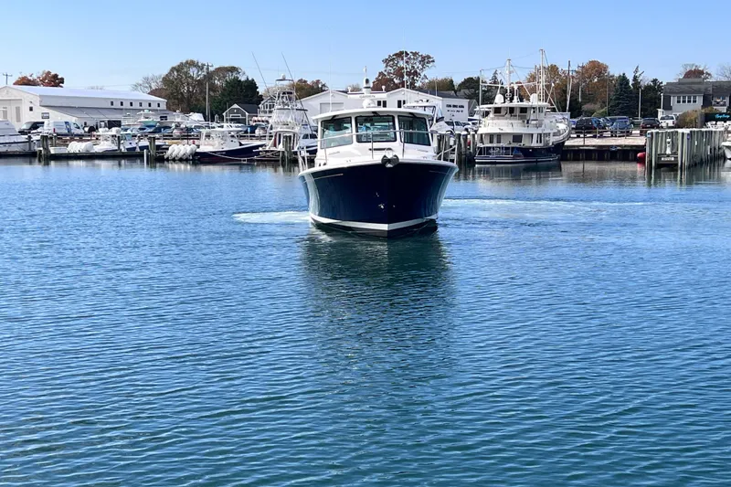 Slide: The Image of 2024 Back Cove 39O boat cruising in a marina with other vessels docked nearby. - 1