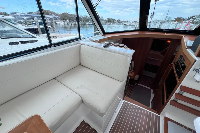 Slide: The Image of 2024 Back Cove 39O yacht interior with plush seating and scenic marina view. - 19