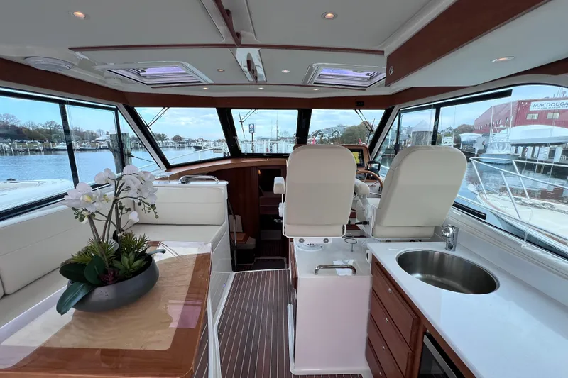 Slide: The Image of 2024 Back Cove 39O yacht interior with helm, seating, and kitchenette overlooking marina. - 28