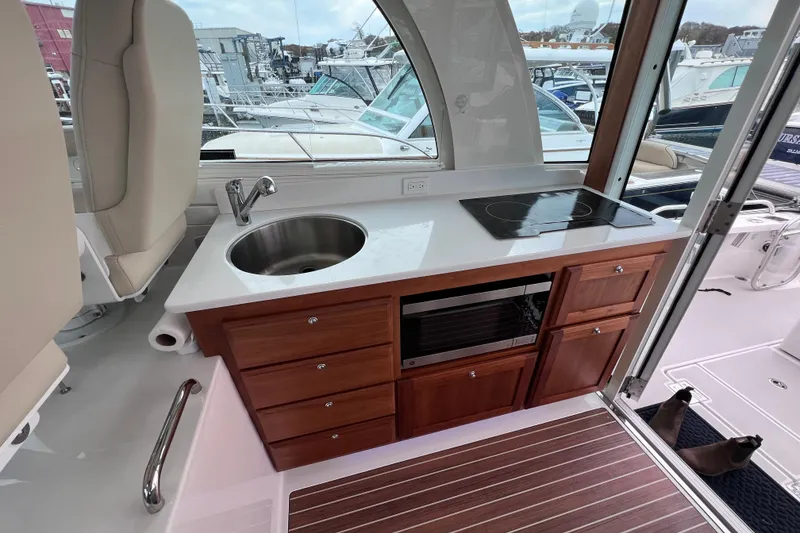Slide: The Image of 2024 Back Cove 39O yacht interior with kitchenette, featuring sink, stove, and wooden cabinetry. - 30