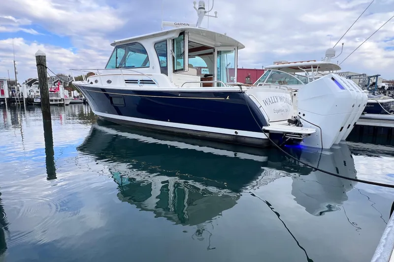 Slide: The Image of 2024 Back Cove 39O boat docked in marina, reflecting on calm water under cloudy sky. - 6