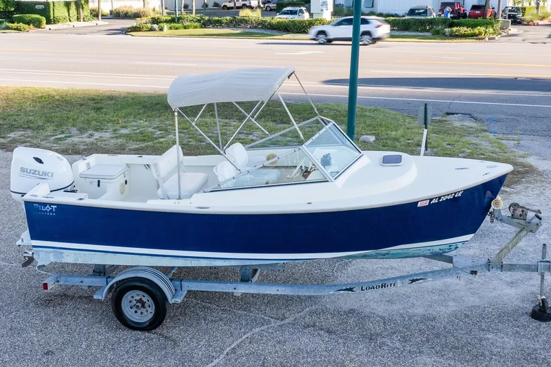 Slide: The Image of 2004 Hoby Pilot 19 boat with Suzuki engine on trailer, parked near road. - 0