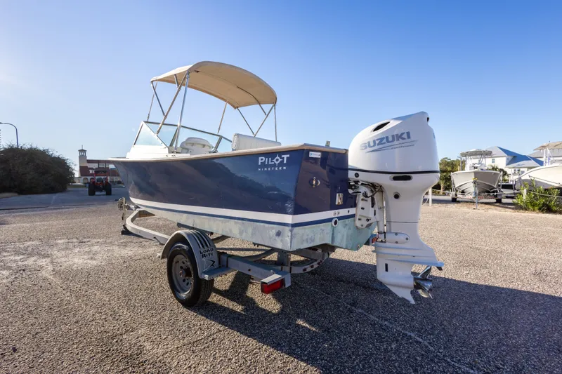 Slide: The Image of 2004 Hoby Pilot 19 boat with Suzuki outboard motor on trailer, parked outdoors. - 13