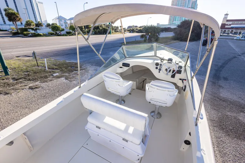 Slide: The Image of 2004 Hoby Pilot 19 boat with canopy, parked near a road, featuring white seating. - 16