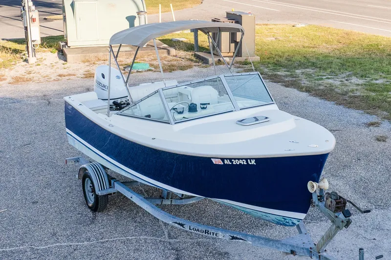 Slide: The Image of 2004 Hoby Pilot 19 boat on trailer with Suzuki outboard motor, parked on gravel. - 4