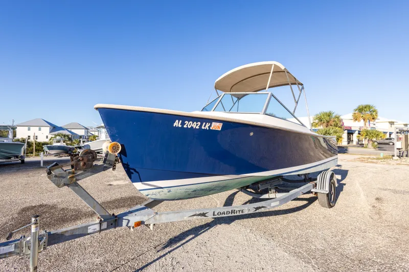 Slide: The Image of 2004 Hoby Pilot 19 boat on trailer, blue hull, sunny day, outdoor setting. - 6