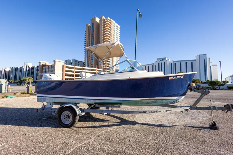Slide: The Image of 2004 Hoby Pilot 19 boat on trailer, urban background, clear sky. - 7