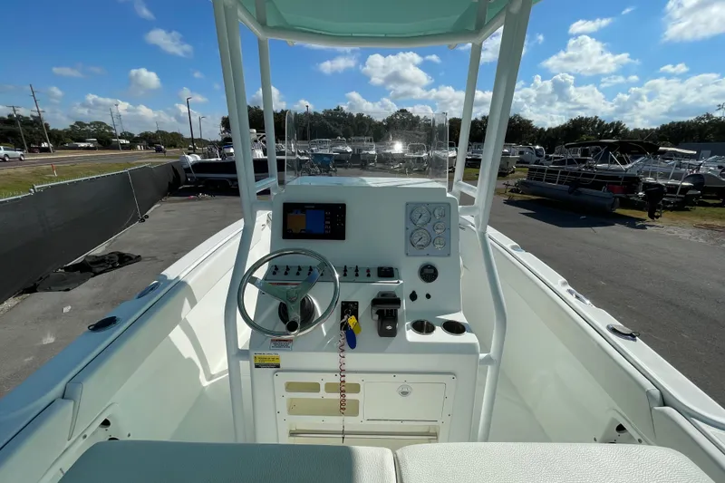 Slide: The Image of 2021 Clearwater 2200 boat dashboard with steering wheel and controls under a clear blue sky. - 15