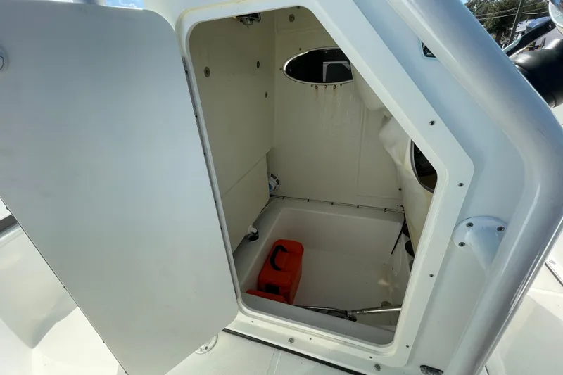 Slide: The Image of Open storage compartment in 2021 Clearwater 2200 boat, featuring a white interior and orange container. - 24