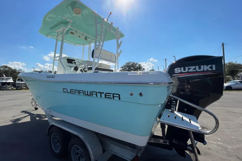 Slide: The Image of 2021 Clearwater 2200 boat with Suzuki engine, parked on a trailer under sunny skies. - 6
