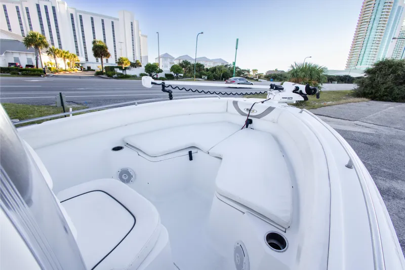 Slide: The Image of 2010 Sea Hunt Ultra 210 boat interior with seating, parked near a road and buildings. - 18