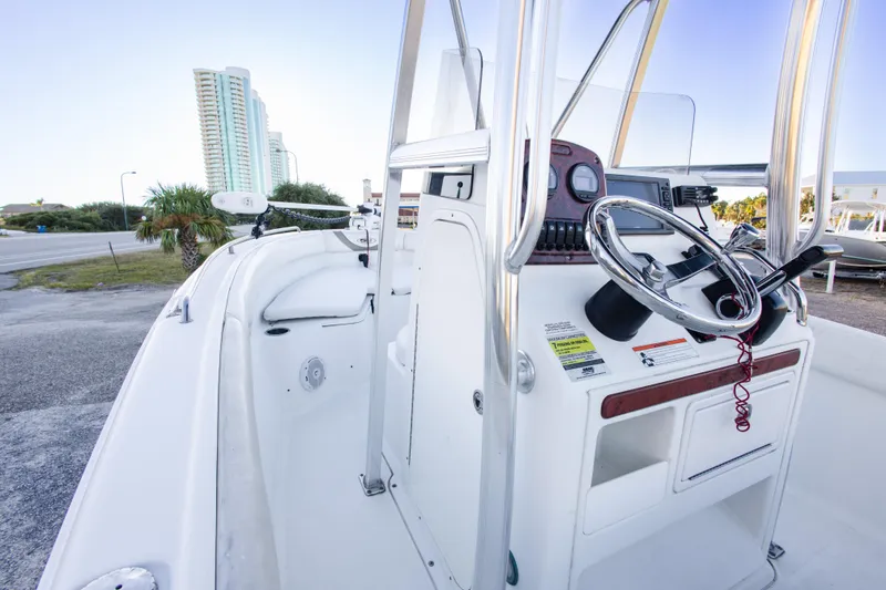 Slide: The Image of 2010 Sea Hunt Ultra 210 boat interior with steering console, near coastal buildings. - 23