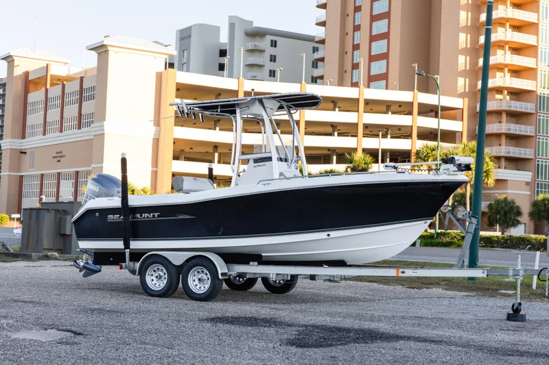 Slide: The Image of 2010 Sea Hunt Ultra 210 boat on trailer, parked near modern buildings. - 3