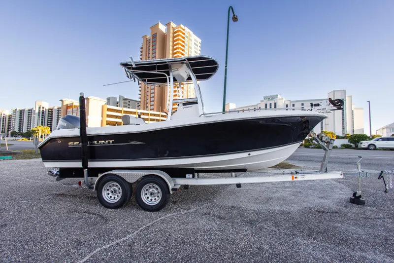 Slide: The Image of 2010 Sea Hunt Ultra 210 boat on trailer, parked near modern buildings. - 9