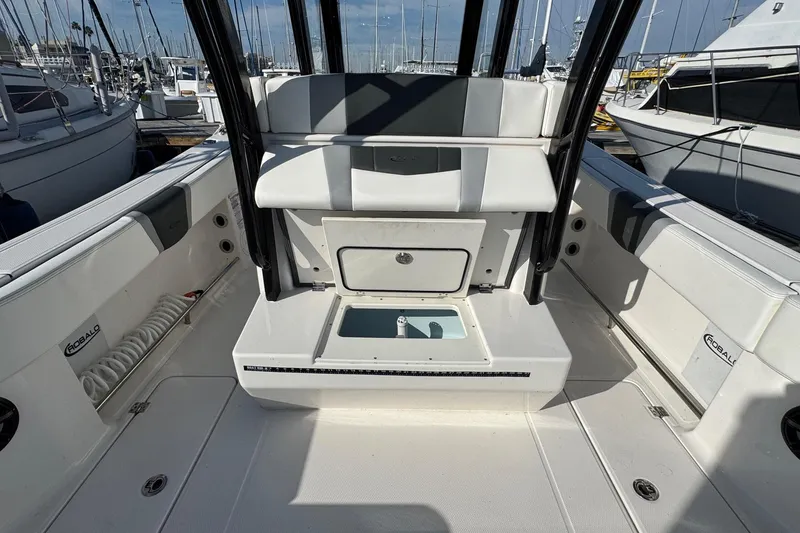 Slide: The Image of 2025 Robalo R270 Center Console boat interior with seating and storage, docked at marina. - 23