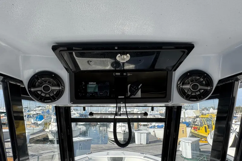 Slide: The Image of 2025 Robalo R270 Center Console interior with speakers and control panel, docked at marina. - 30