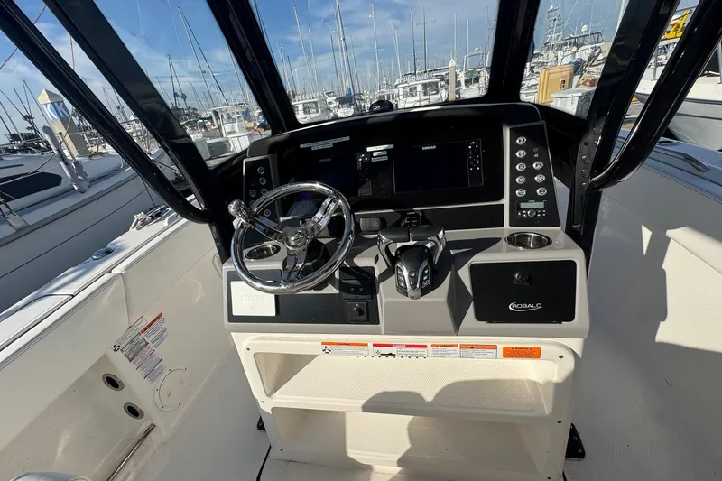 Slide: The Image of 2025 Robalo R270 Center Console boat dashboard with steering wheel and controls. - 33