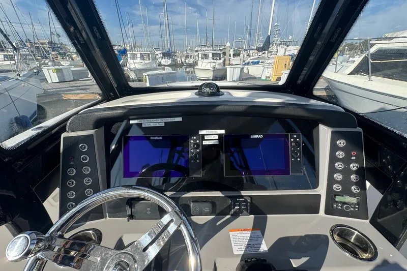 Slide: The Image of 2025 Robalo R270 Center Console boat dashboard with navigation screens and steering wheel. - 34