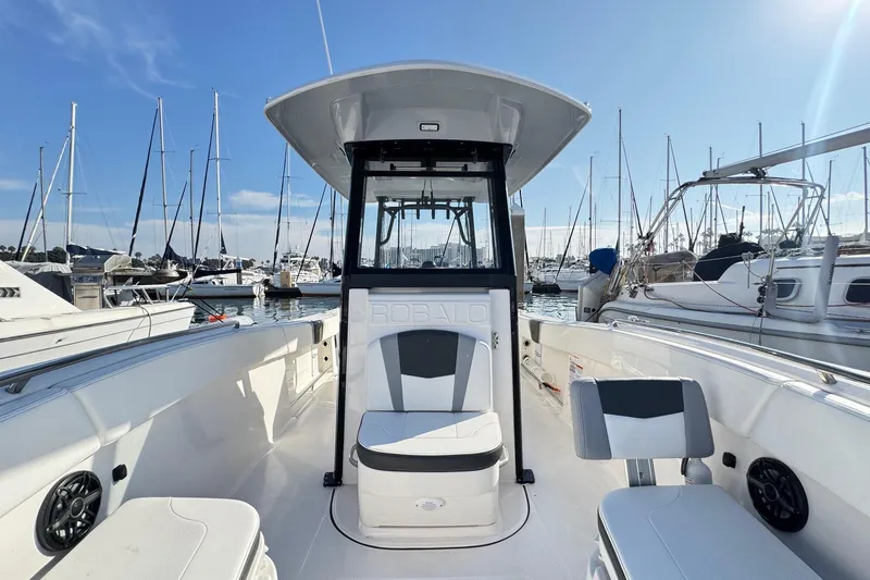 Slide: The Image of 2025 Robalo R270 Center Console boat docked in a marina, surrounded by sailboats. - 46