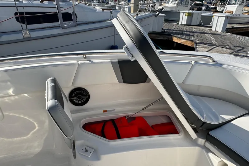 Slide: The Image of 2025 Robalo R270 Center Console boat with open storage compartment at marina. - 50