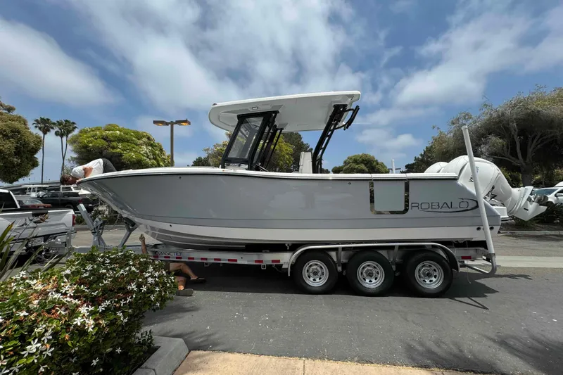 Slide: The Image of 2025 Robalo R270 Center Console boat on a trailer, parked outdoors. - 52