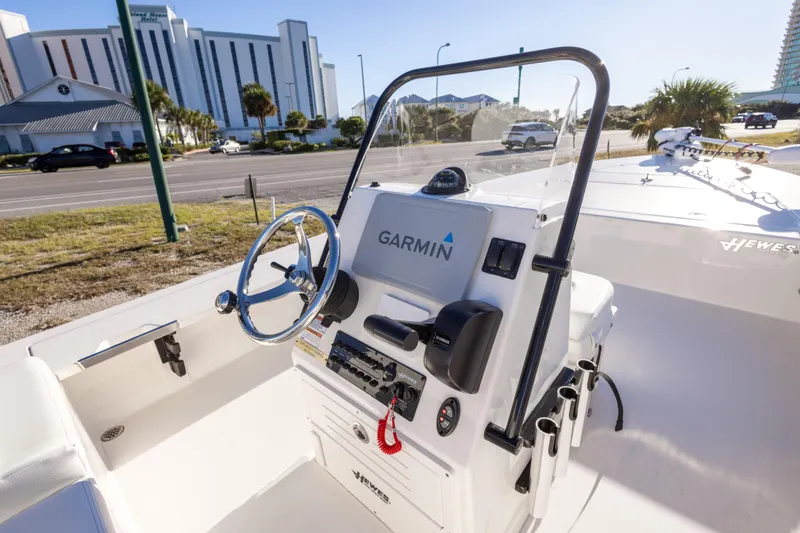 Slide: The Image of 2023 Hewes Redfisher 21 boat with Garmin navigation, parked near a road and buildings. - 15