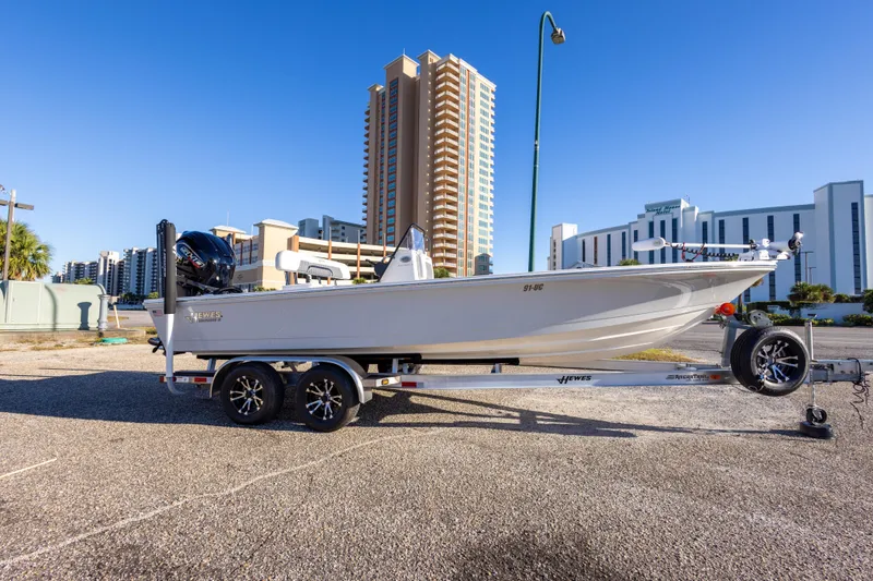 Slide: The Image of 2023 Hewes Redfisher 21 boat on trailer, urban backdrop, clear blue sky. - 6